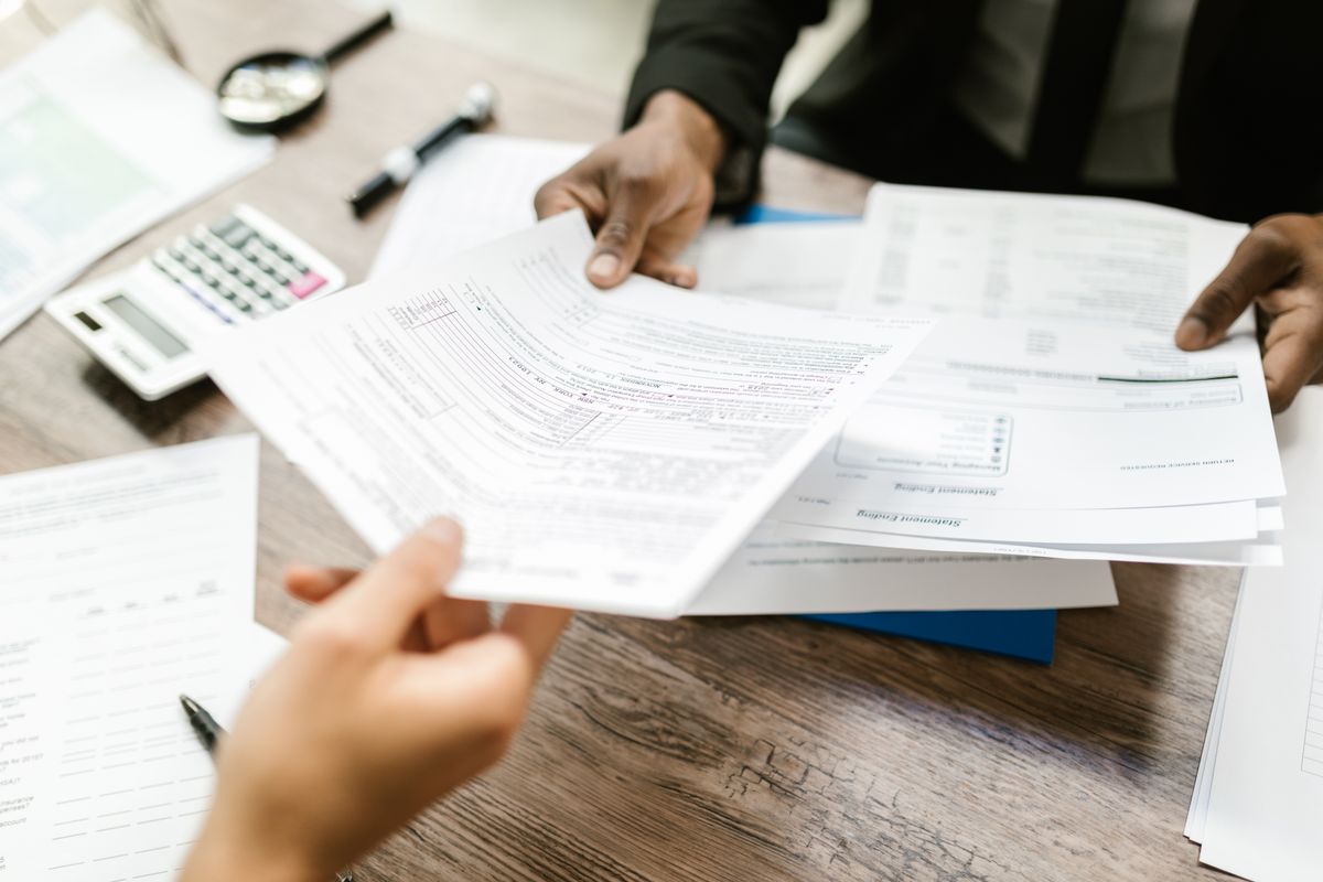 Two people handing off completed project documents
