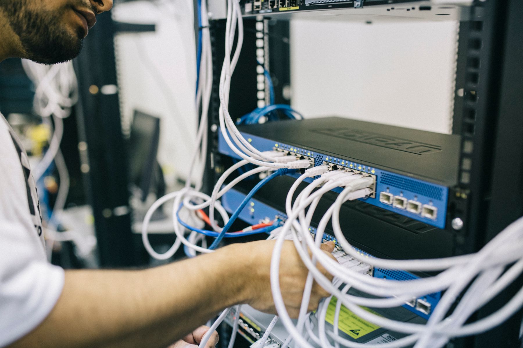 Technician working inside a network equipment rack
